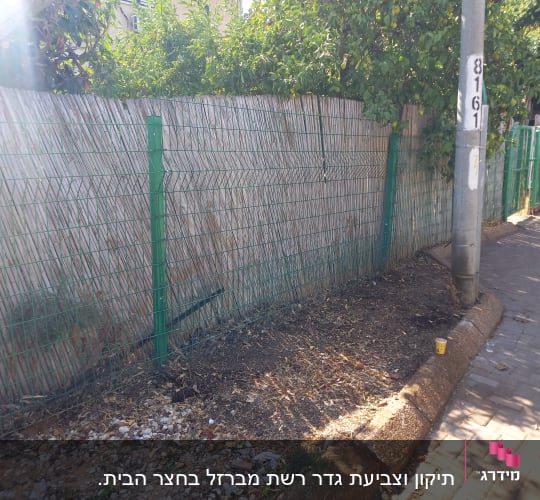 גדר מתכת ירוקה לאורך שביל עם עמוד חשמל